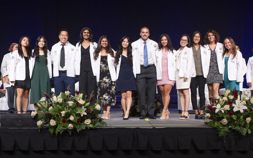 A group of COMP students posing for a photo on stage.