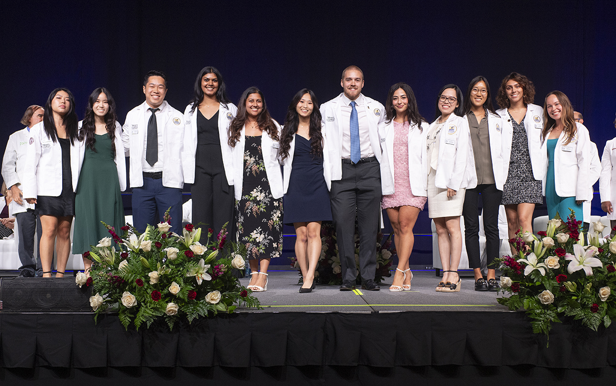 A group of COMP students posing for a photo on stage.